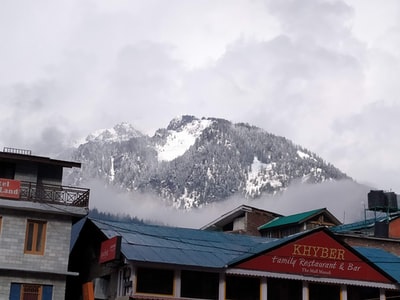 During the day, the snow mountain near the brown wooden house
